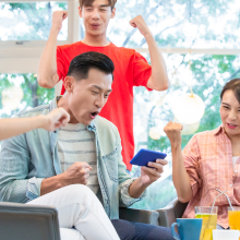 友人たちと一つのスマートフォンで試合観戦して盛り上がっている男性