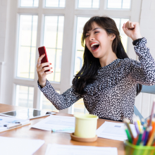 自宅でスマートフォンで試合観戦をして歓喜している女性